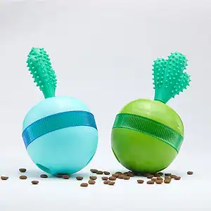 Two pet toys with green stems, one blue and one green, sit on a white background with brown pellets scattered below.