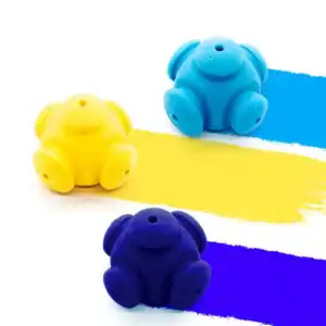 Three bear-shaped silicone cable organizers in yellow, blue, and dark blue rest on matching paint streaks on a white background.