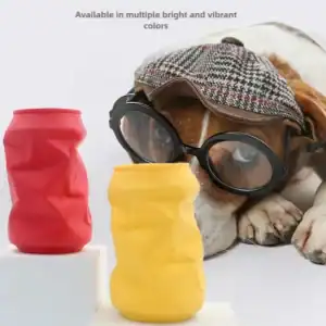 A dog in glasses and hat looks at crumpled red and yellow cans on white. Text: "Available in vibrant colors.