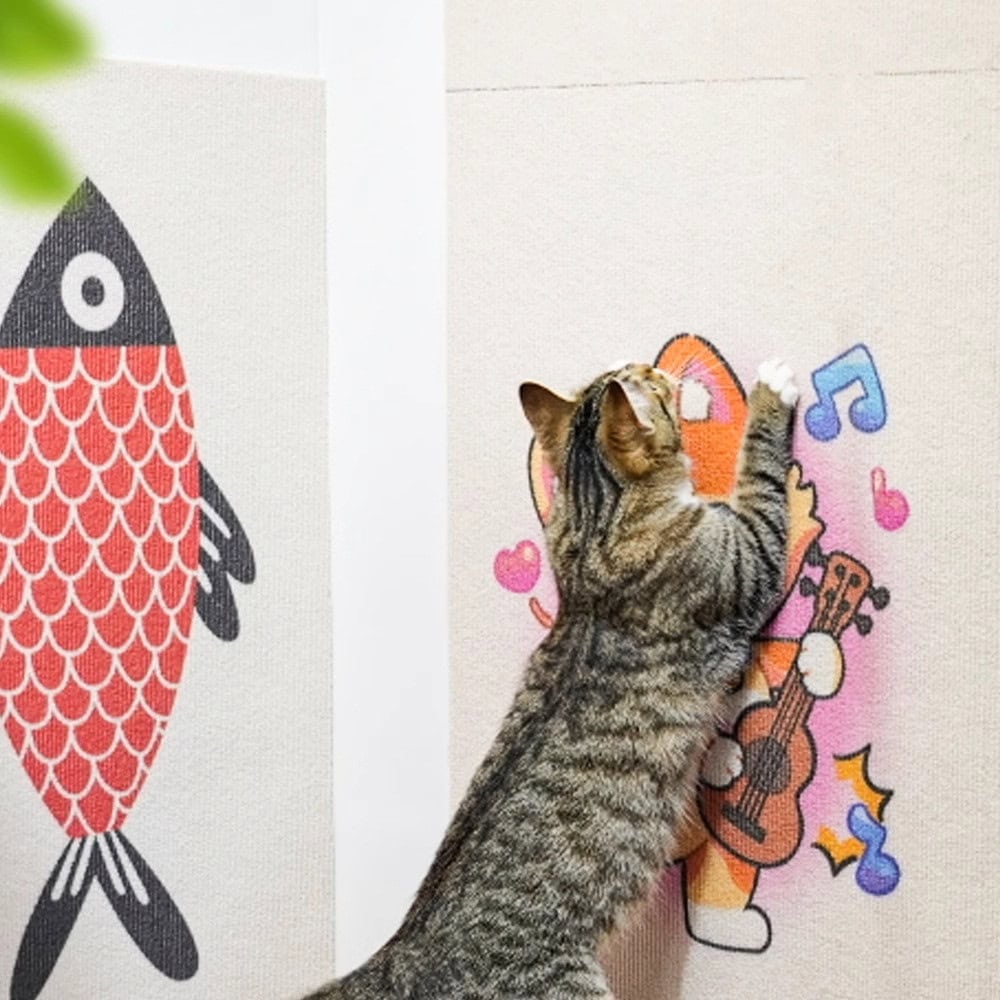 A tabby cat scratches a colorful cartoon-themed scratching pad with fish and guitar-playing character designs.
