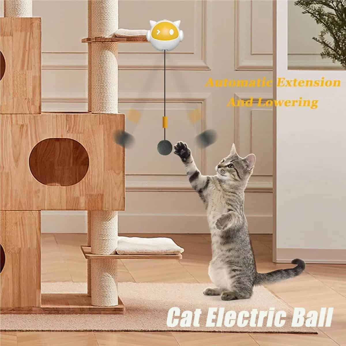 Gray tabby cat plays with an automatic retractable teaser ball toy near a wooden cat tree.