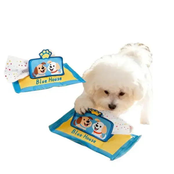Adorable white puppy playing with Blue House branded pet wipes, emphasizing pet care and hygiene products.