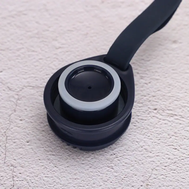 Close-up of HEOU wireless earbuds charging case on textured surface, showcasing sleek black design and circular charging port.