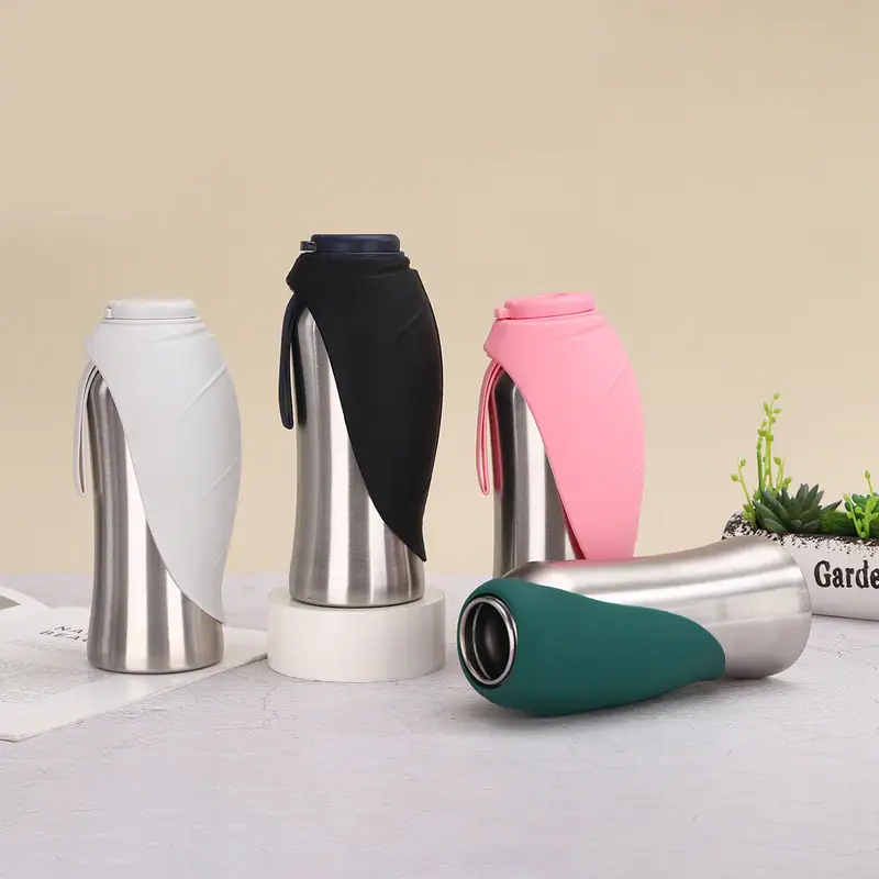 Set of four stainless steel travel mugs with colorful silicone sleeves in white, black, pink, and green, placed on a light surface with a small plant in the background.