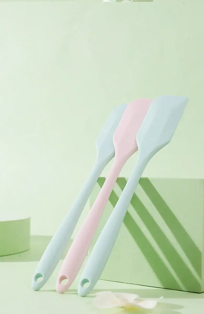 Set of three pastel-colored toothbrushes in light blue and pink, arranged on a minimalist green and white background for a fresh, clean aesthetic.