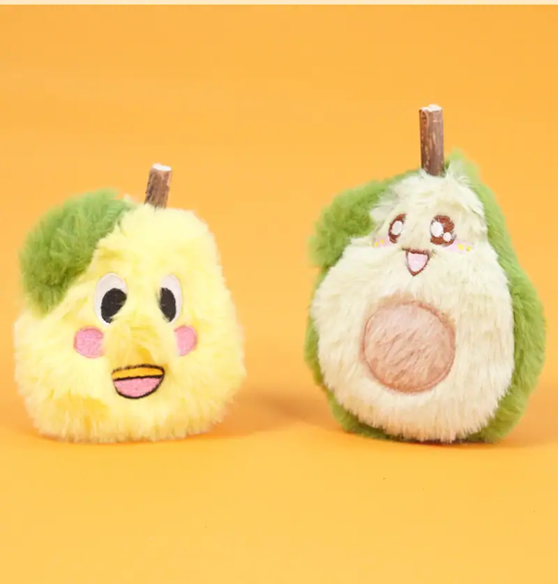 Two plush pears with embroidered faces, one with a surprised expression and the other with a happy face, set against a bright orange background.
